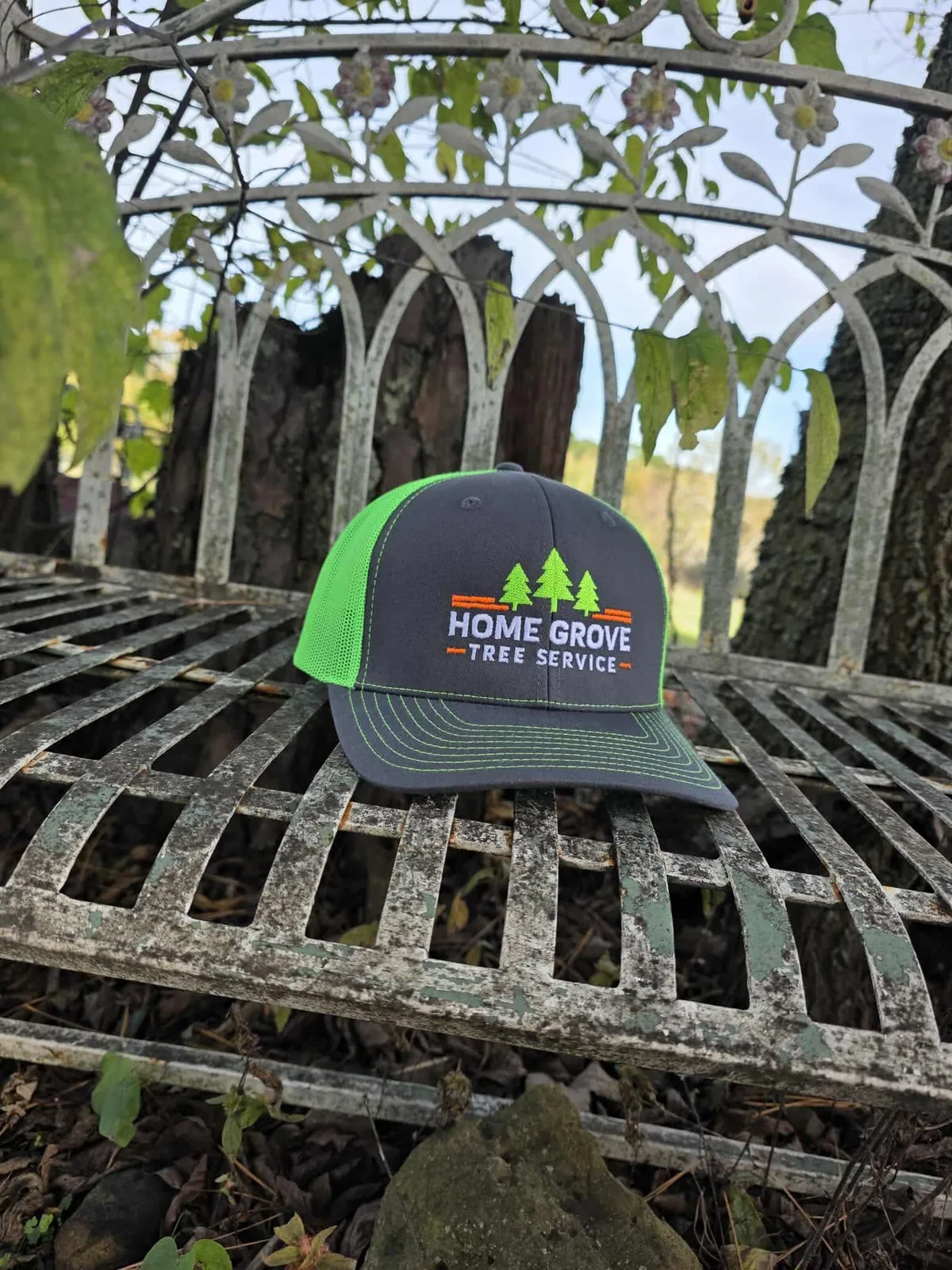 Home Grove Tree Service branded hat on a bench outdoors